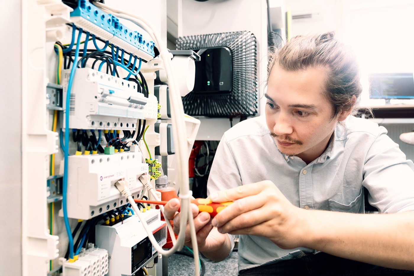 An engineer wiring a test setup in a distribution cabinet in the EnQS Testlab